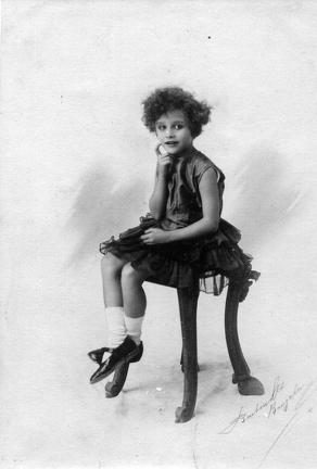 Studio portrait of a young girl sitting on a stool