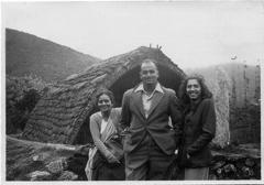 Man and two women outside a hut