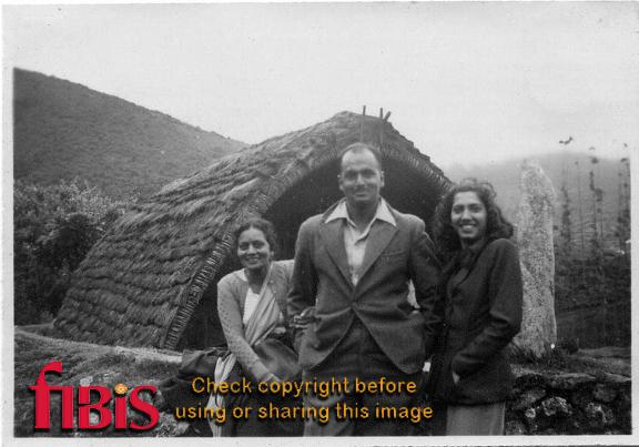 Man and two women outside a hut
